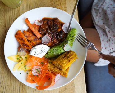 Colorful vegetarian meal with avocado, beans, and corn served on a wooden table. Ideal for healthy lifestyle visuals.