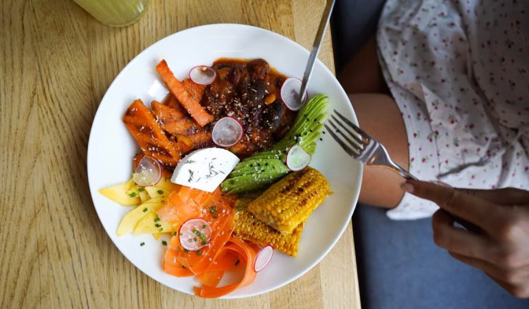 Colorful vegetarian meal with avocado, beans, and corn served on a wooden table. Ideal for healthy lifestyle visuals.
